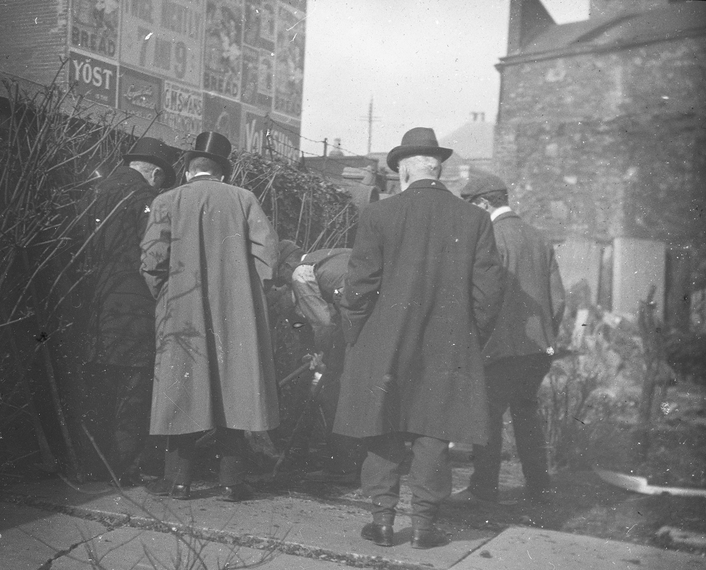 This photo again shows the western wall of the graveyard, but includes some interesting advertisements of the time.