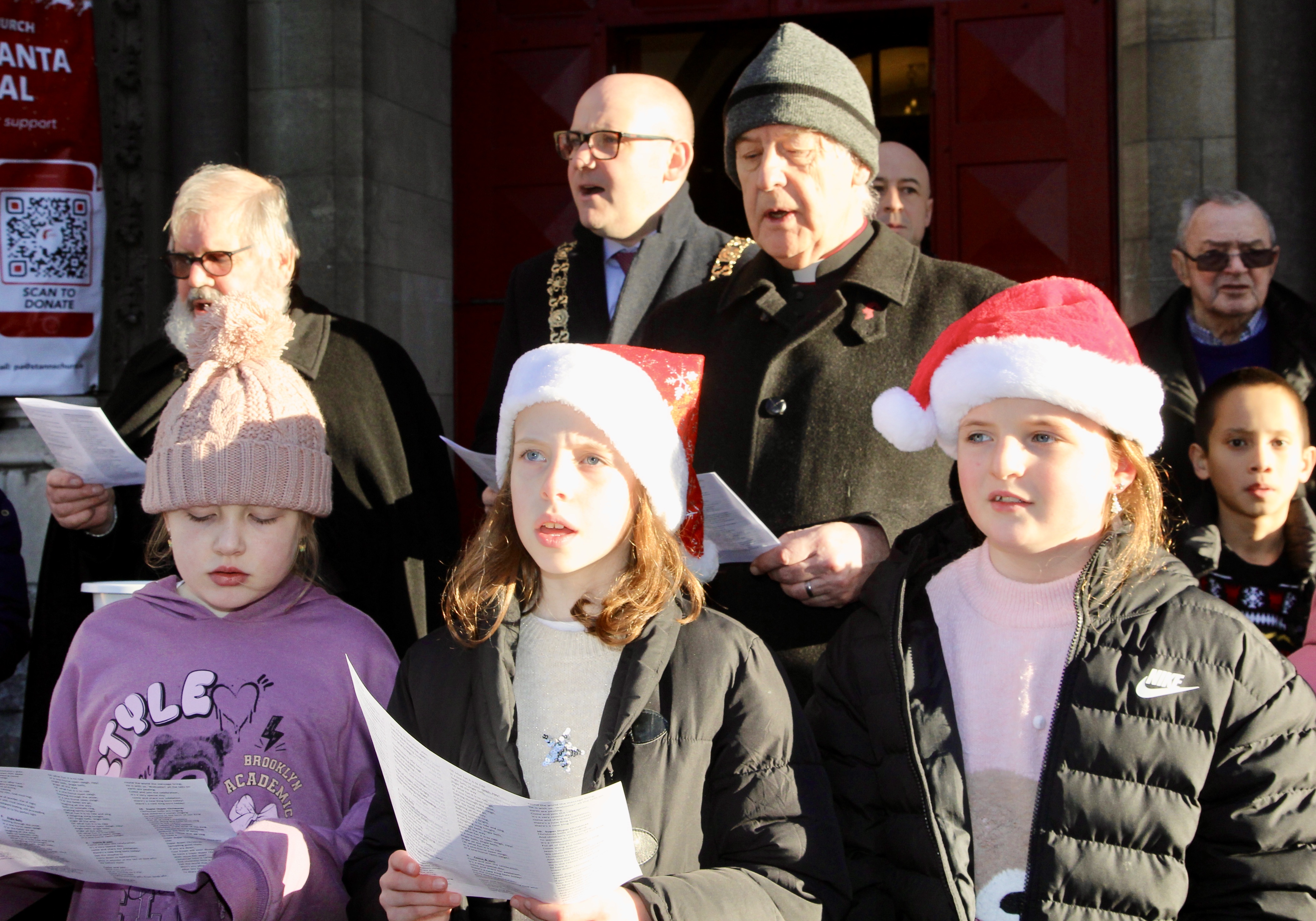St Ann's caretaker Fred Deane, Lord Mayor of Dublin Cllr Ray McAdam and Archbishop Michael Jackson sing along with the choir of Kildare Place School at the launch of Black Santa 2025.