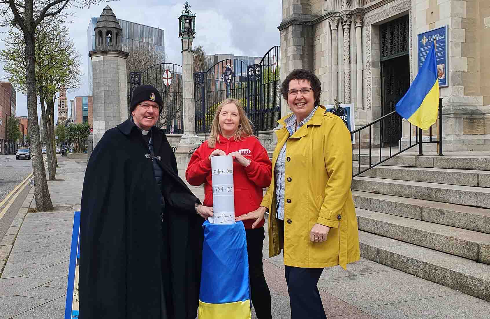 Dean Stephen Forde has presented a cheque for &pound;56,784 to Rosamond Bennett, Chief Executive of Christian Aid Ireland, and Jenny Williams, Chief Executive of Habitat for Humanity Ireland, raised through Belfast Cathedral's special Black Santa Sit-out for Ukraine.